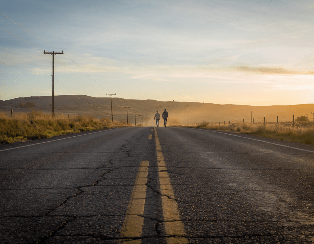 Two people walking on a long road